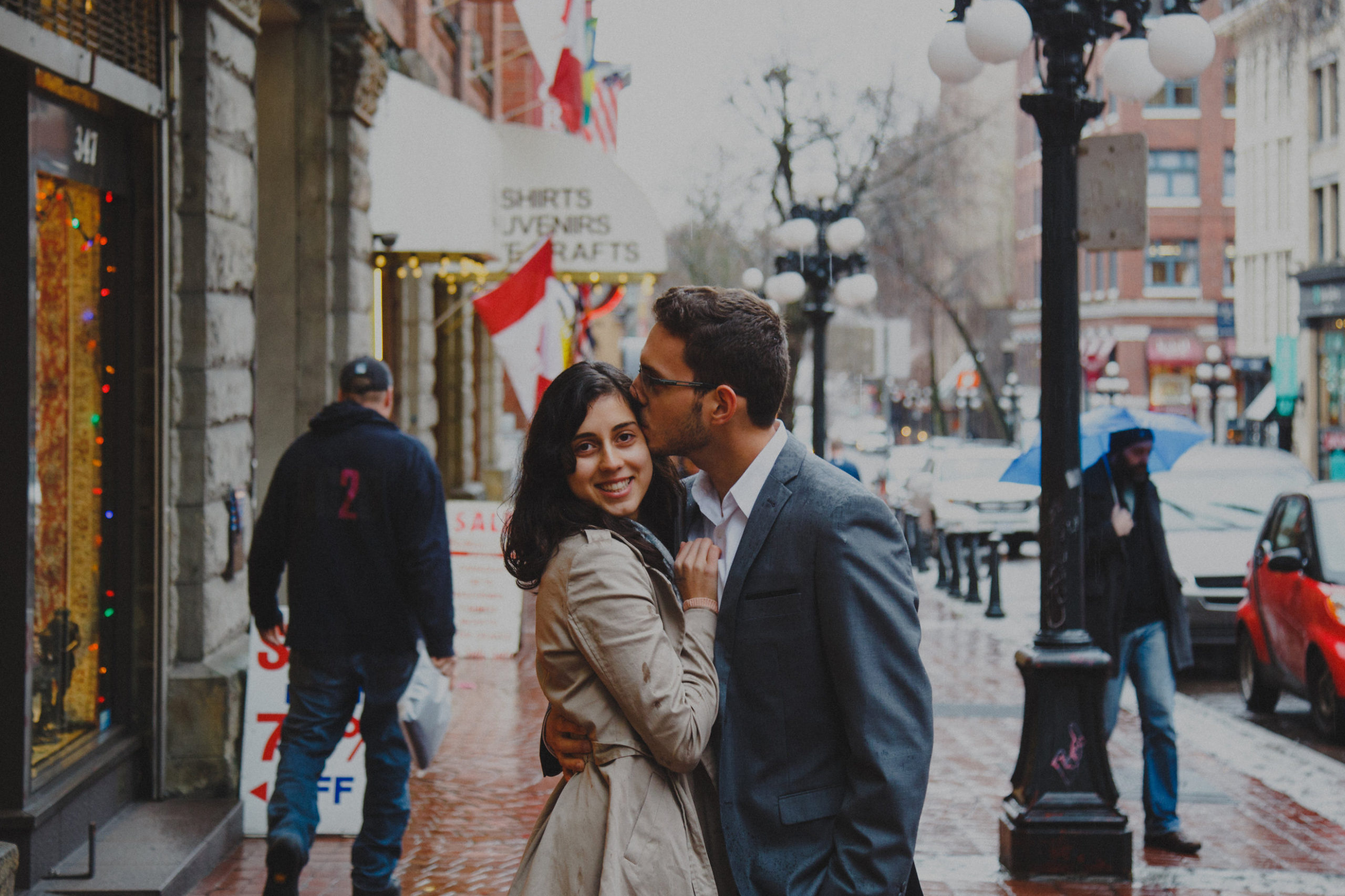 Man kisses wife on cheek on sidewalk in Gastown